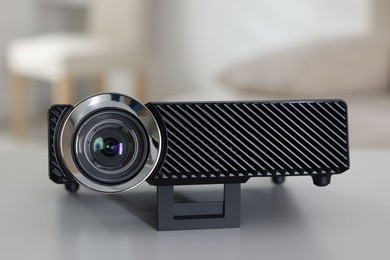Photo of Modern video projector on white table indoors, closeup