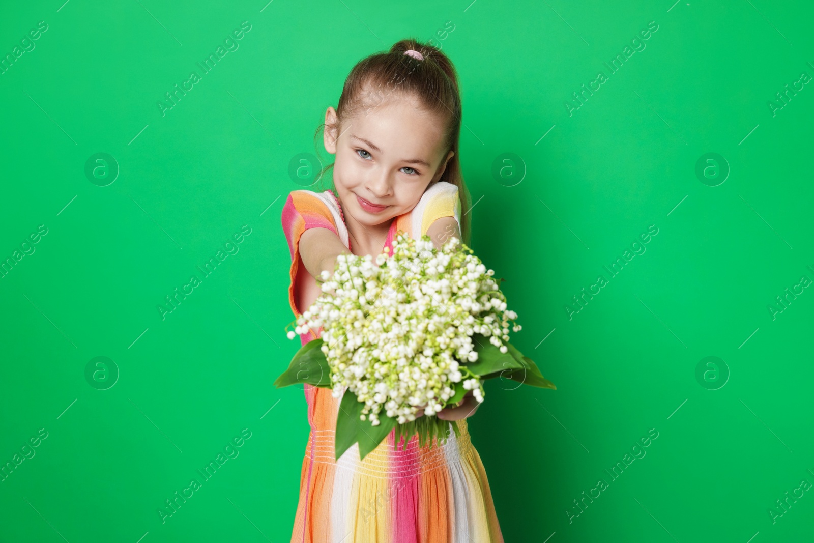 Girl with bouquet of beautiful lily-of-the-valley flowers on green background Photo of Girl with bouquet of beautiful lily-of-the-valley flowers on green background