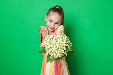 Photo of Girl with bouquet of beautiful lily-of-the-valley flowers on green background