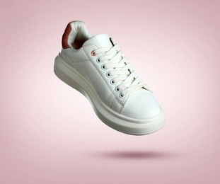Image of Stylish sneaker in air on dusty pink gradient background
