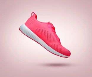 Image of Stylish sneaker in air on dusty pink gradient background