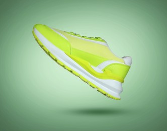 Image of Fashionable sneaker in air on green gradient background