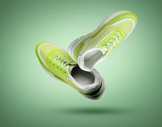 Image of Fashionable sneakers in air on green gradient background
