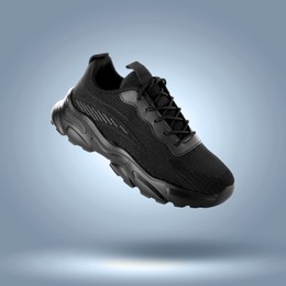 Image of Fashionable black sneaker in air on blue grey gradient background
