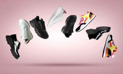 Image of Different stylish sneakers in air on dusty pink gradient background