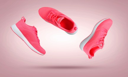 Image of Stylish sneakers in air on dusty pink gradient background