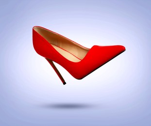 Image of Stylish red high heeled shoe in air on light blue gradient background