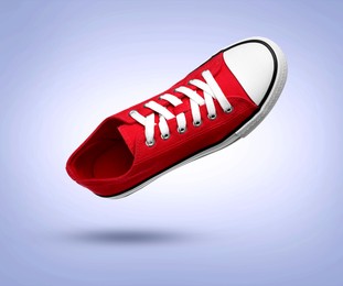 Image of Stylish red sneaker in air on light blue gradient background