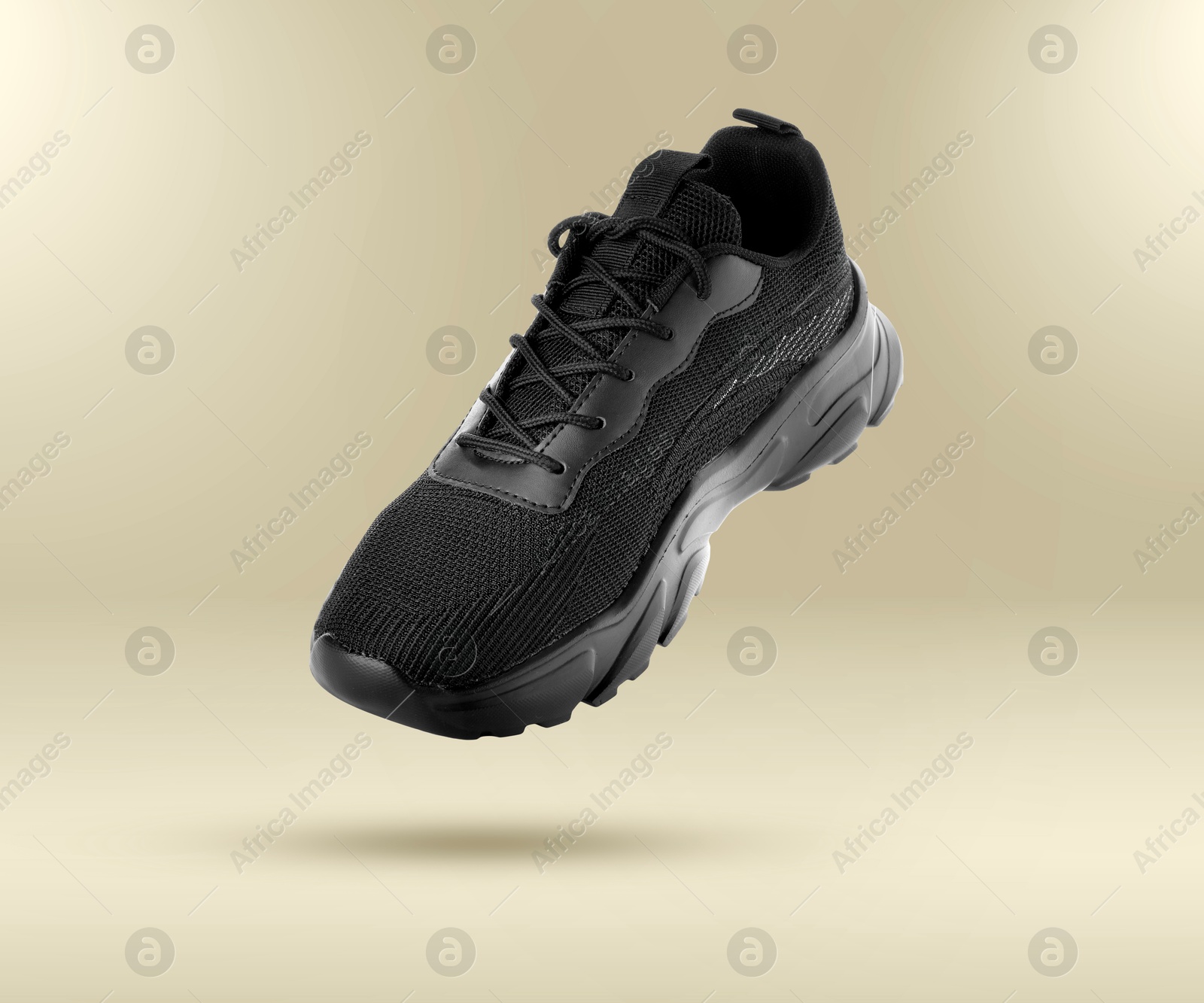 Fashionable black sneaker in air on beige gradient background Image of Fashionable black sneaker in air on beige gradient background