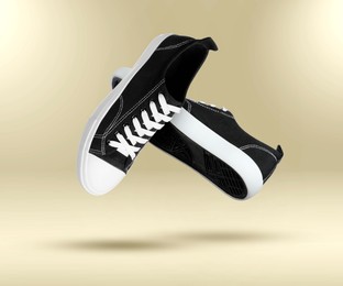 Image of Fashionable sneakers in air on beige gradient background