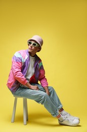 Photo of Fashionable portrait of handsome man in stylish outfit on yellow background