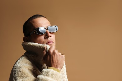 Photo of Fashionable portrait of handsome man in stylish outfit on brown background, space for text
