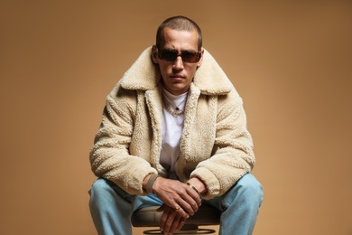 Photo of Fashionable portrait of handsome man in stylish outfit on brown background