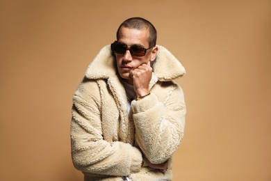 Photo of Fashionable portrait of handsome man in stylish outfit on brown background