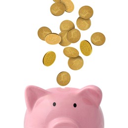 Image of Coins falling into pink piggy bank on white background