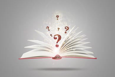 Image of Question marks and magic lights above open book in air against grey background