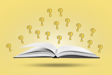 Image of Question marks above open book in air against pale yellow background