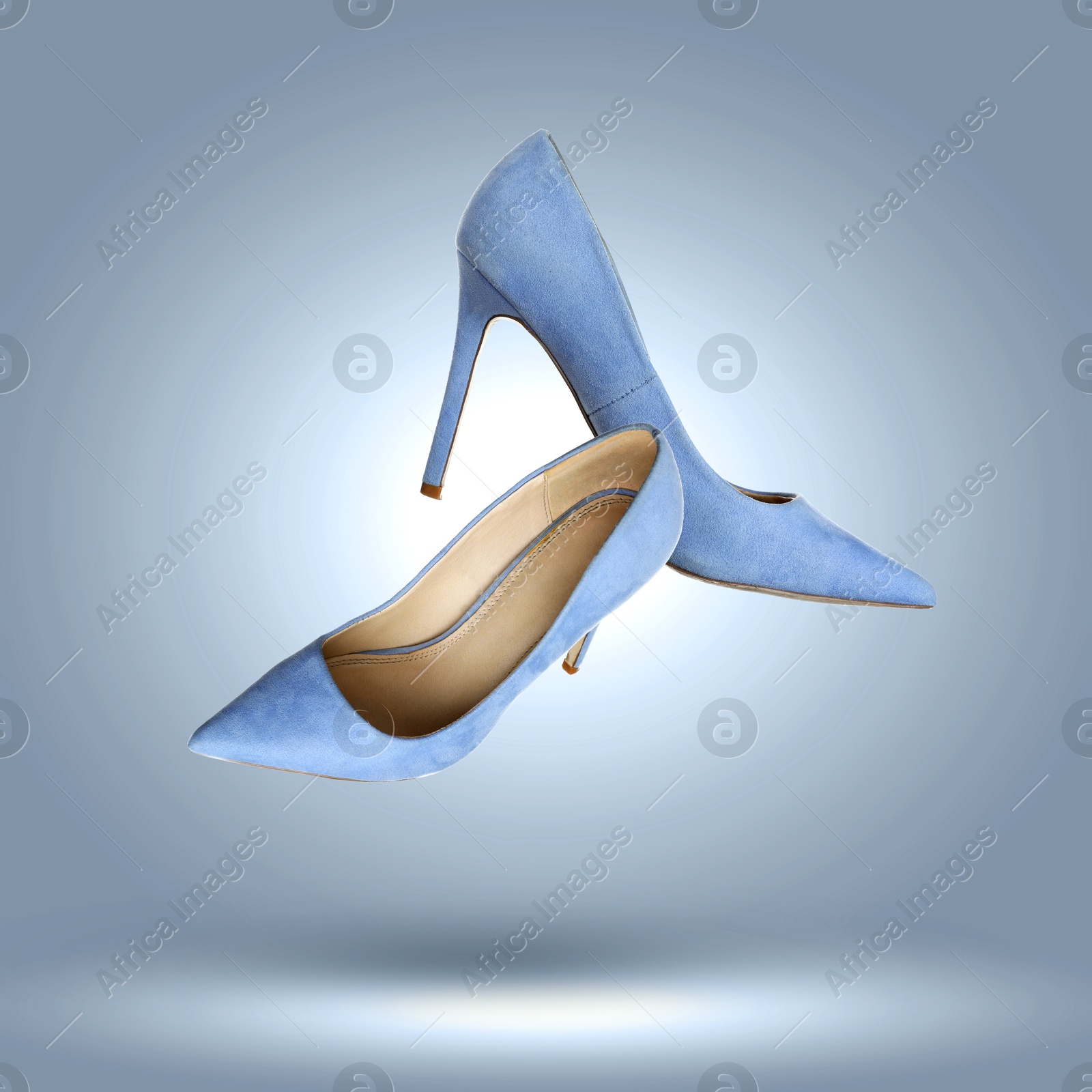 Image of Fashionable high heel shoes in air on blue grey gradient background