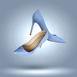 Image of Fashionable high heel shoes in air on blue grey gradient background
