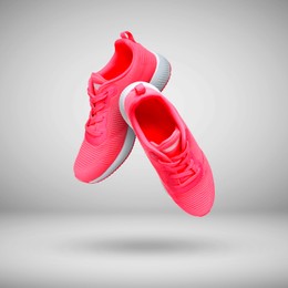 Image of Fashionable pink sneakers in air on grey gradient background