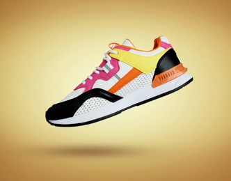 Image of Stylish sneaker in air on golden gradient background