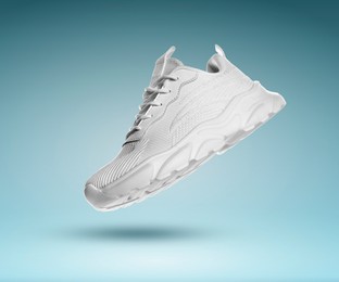 Image of Stylish white sneaker in air on teal gradient background