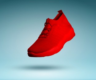 Image of Stylish red sneaker in air on teal gradient background
