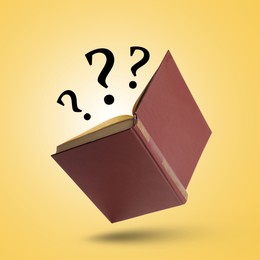 Image of Question marks above open book in air against golden background