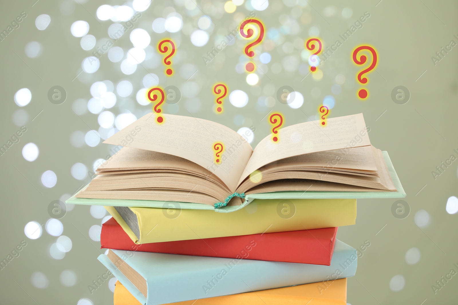 Question marks above open book against grey background with blurred lights Image of Question marks above open book against grey background with blurred lights