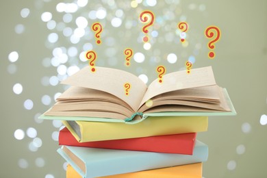 Image of Question marks above open book against grey background with blurred lights