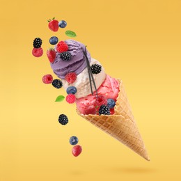 Image of Yummy ice cream balls in wafer cone and berries in air on golden background