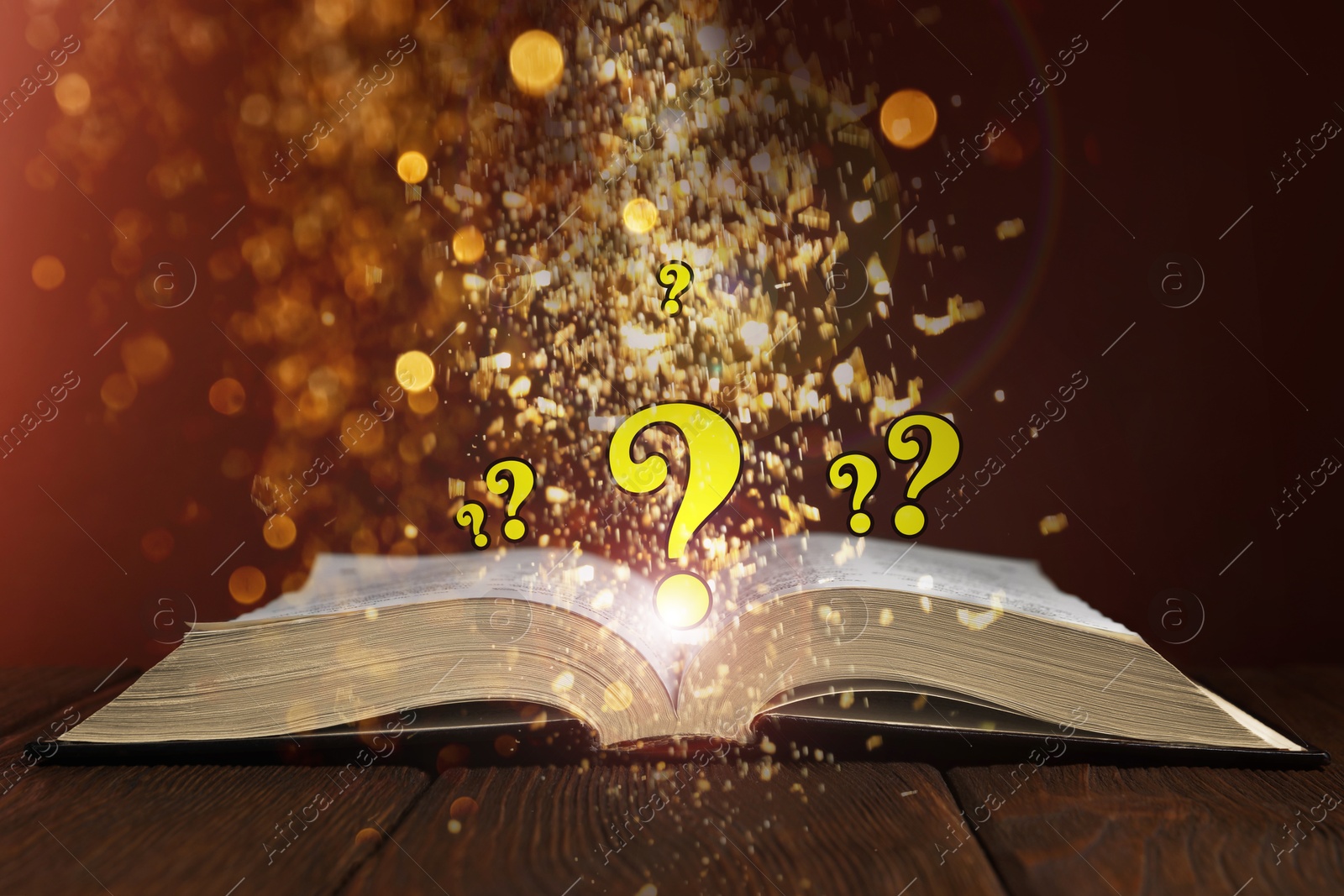 Question marks and magic lights flying out of open book on table against dark background Image of Question marks and magic lights flying out of open book on table against dark background