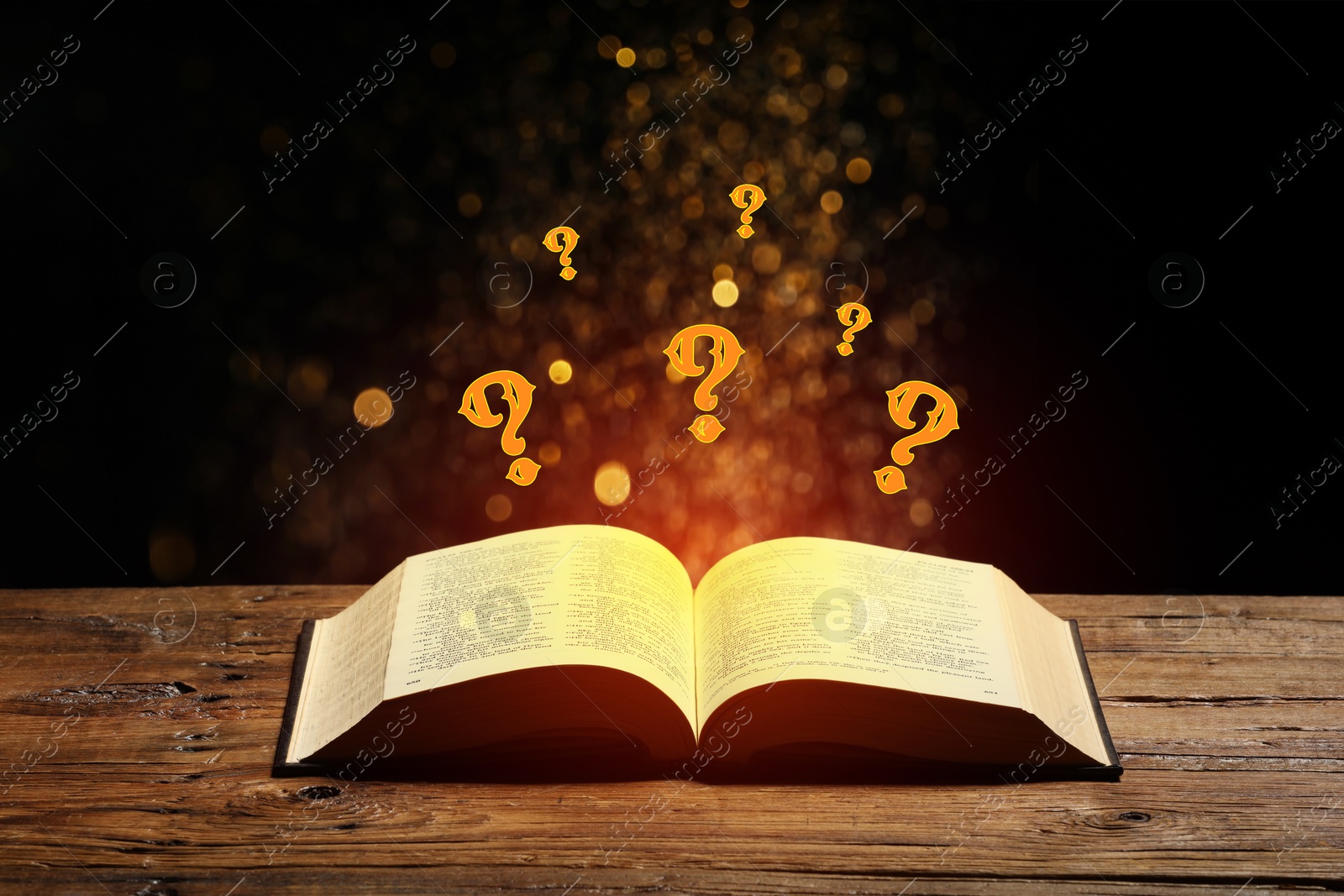 Question marks and magic lights flying out of open book on table against black background Image of Question marks and magic lights flying out of open book on table against black background