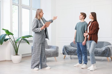 Photo of Smiling real estate agent with tablet working with couple at home