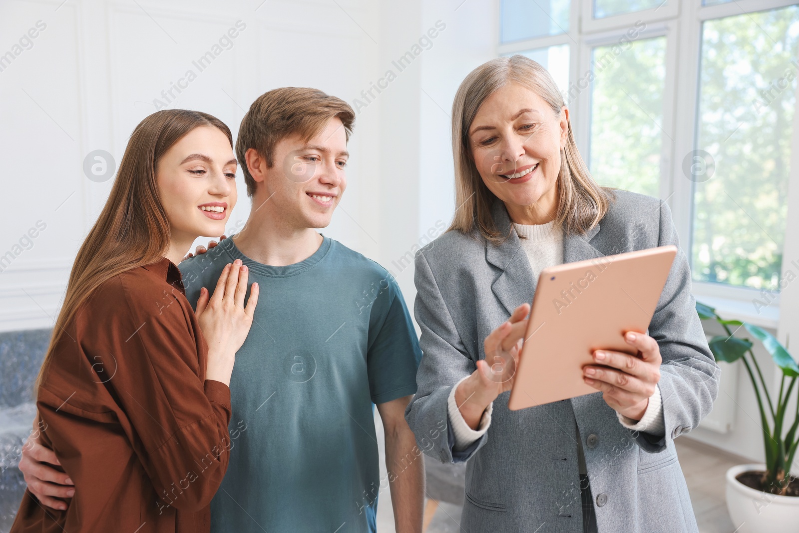 Smiling real estate agent with tablet working with couple at home Photo of Smiling real estate agent with tablet working with couple at home