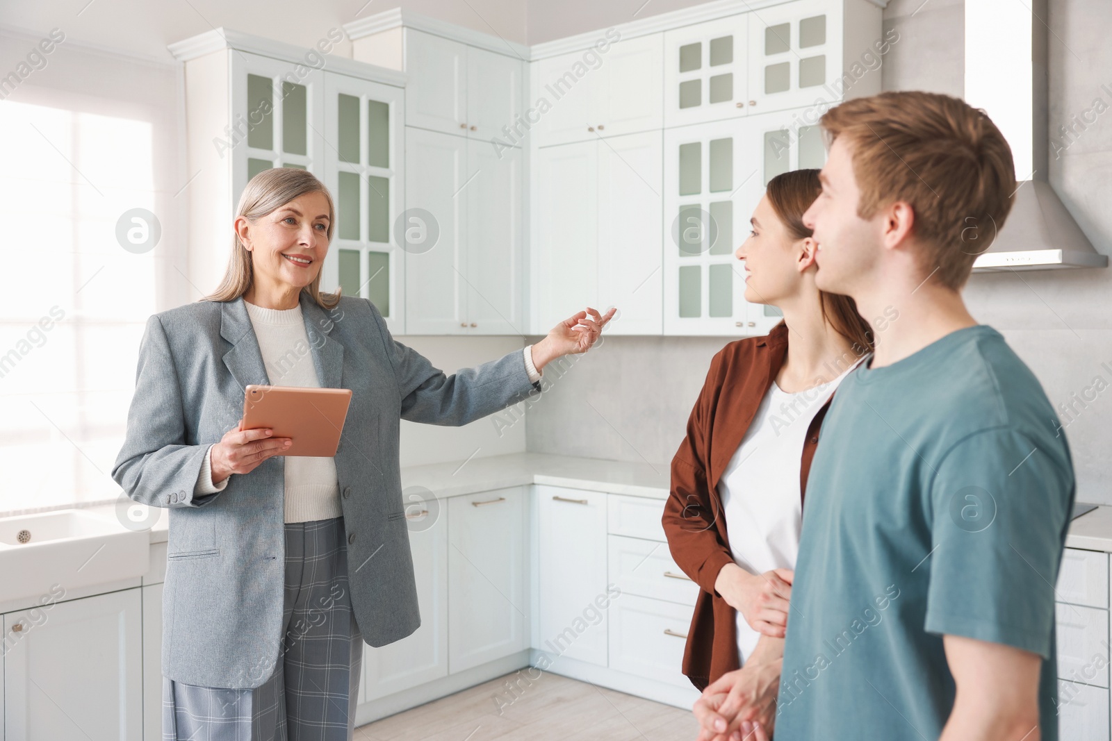 Smiling real estate agent with tablet working with couple in kitchen Photo of Smiling real estate agent with tablet working with couple in kitchen