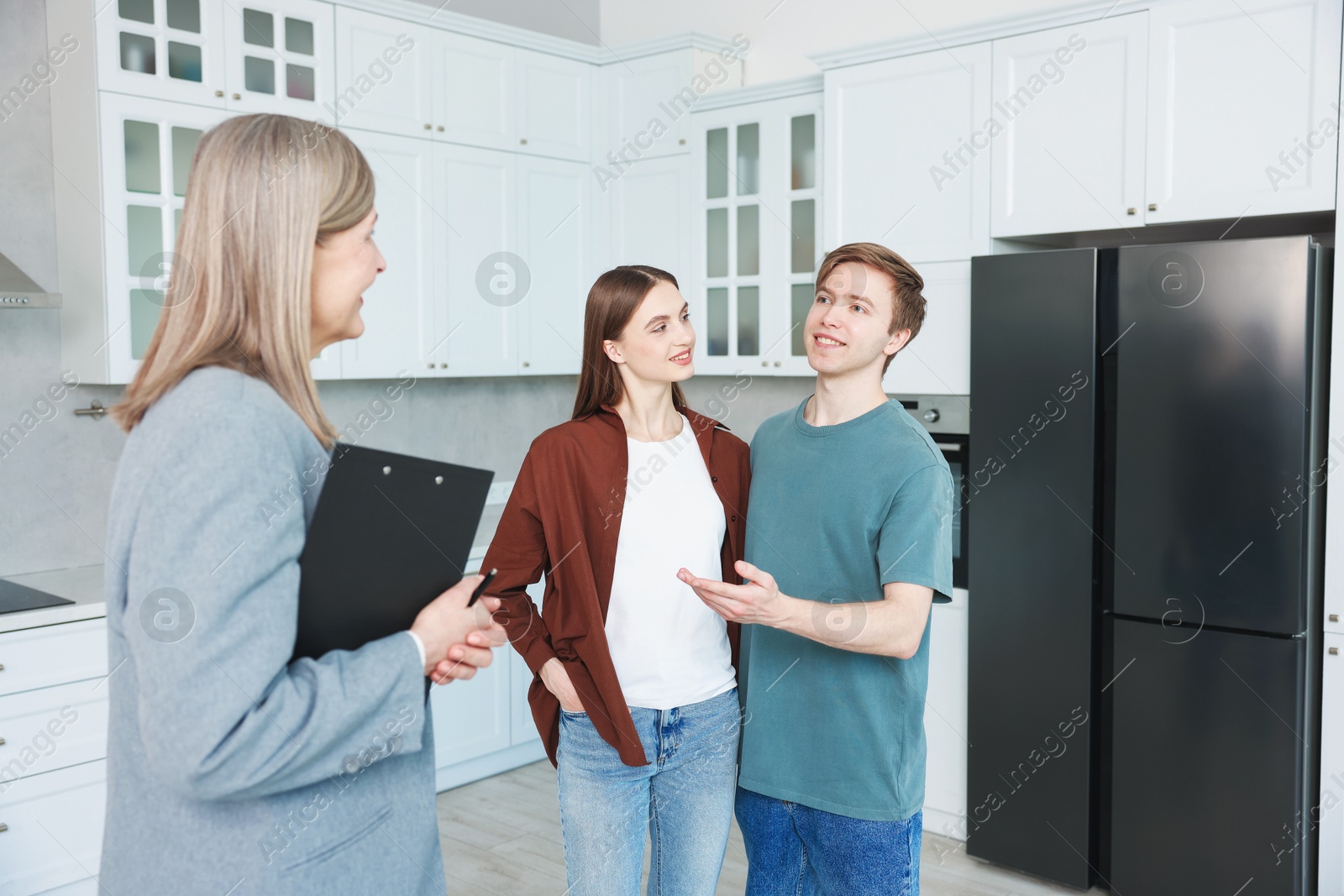 Real estate agent with clipboard working with couple in kitchen Photo of Real estate agent with clipboard working with couple in kitchen