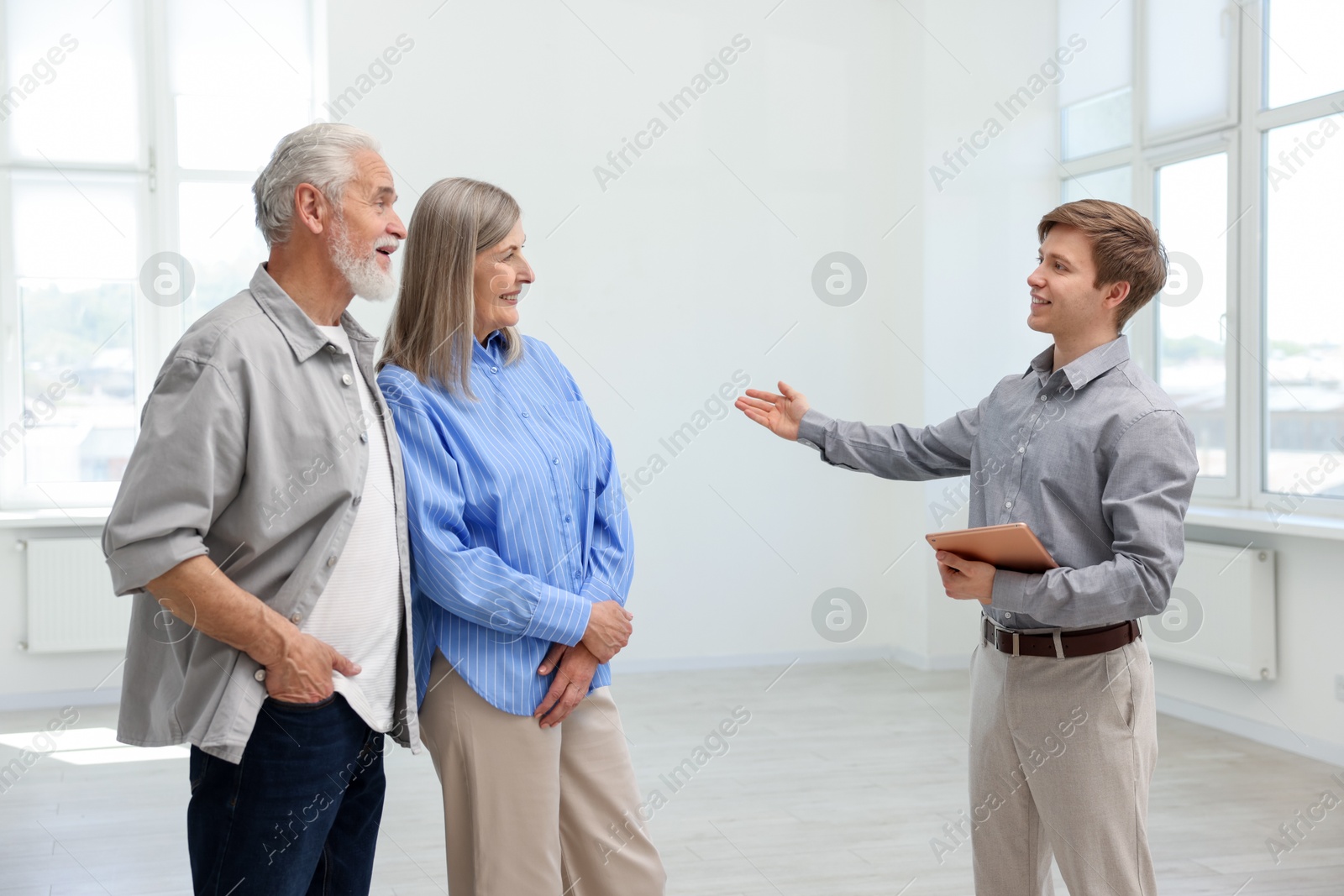 Smiling real estate agent showing apartment to couple indoors Photo of Smiling real estate agent showing apartment to couple indoors