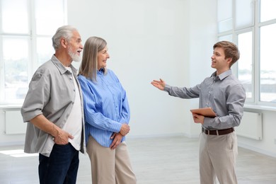 Photo of Smiling real estate agent showing apartment to couple indoors