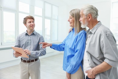 Photo of Smiling real estate agent with tablet working with couple at home