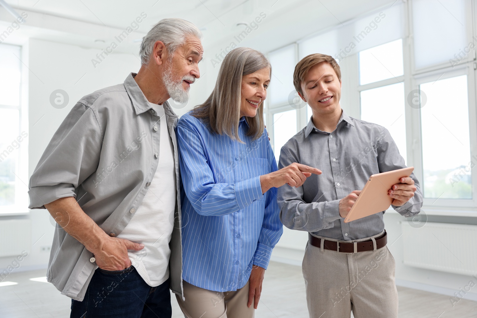 Smiling real estate agent with tablet working with couple at home Photo of Smiling real estate agent with tablet working with couple at home
