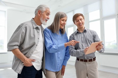 Photo of Smiling real estate agent with tablet working with couple at home