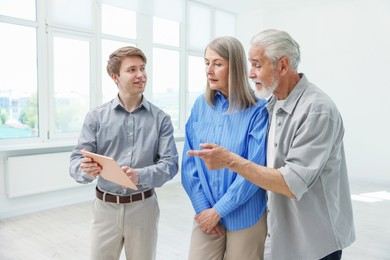 Photo of Smiling real estate agent with tablet working with couple at home