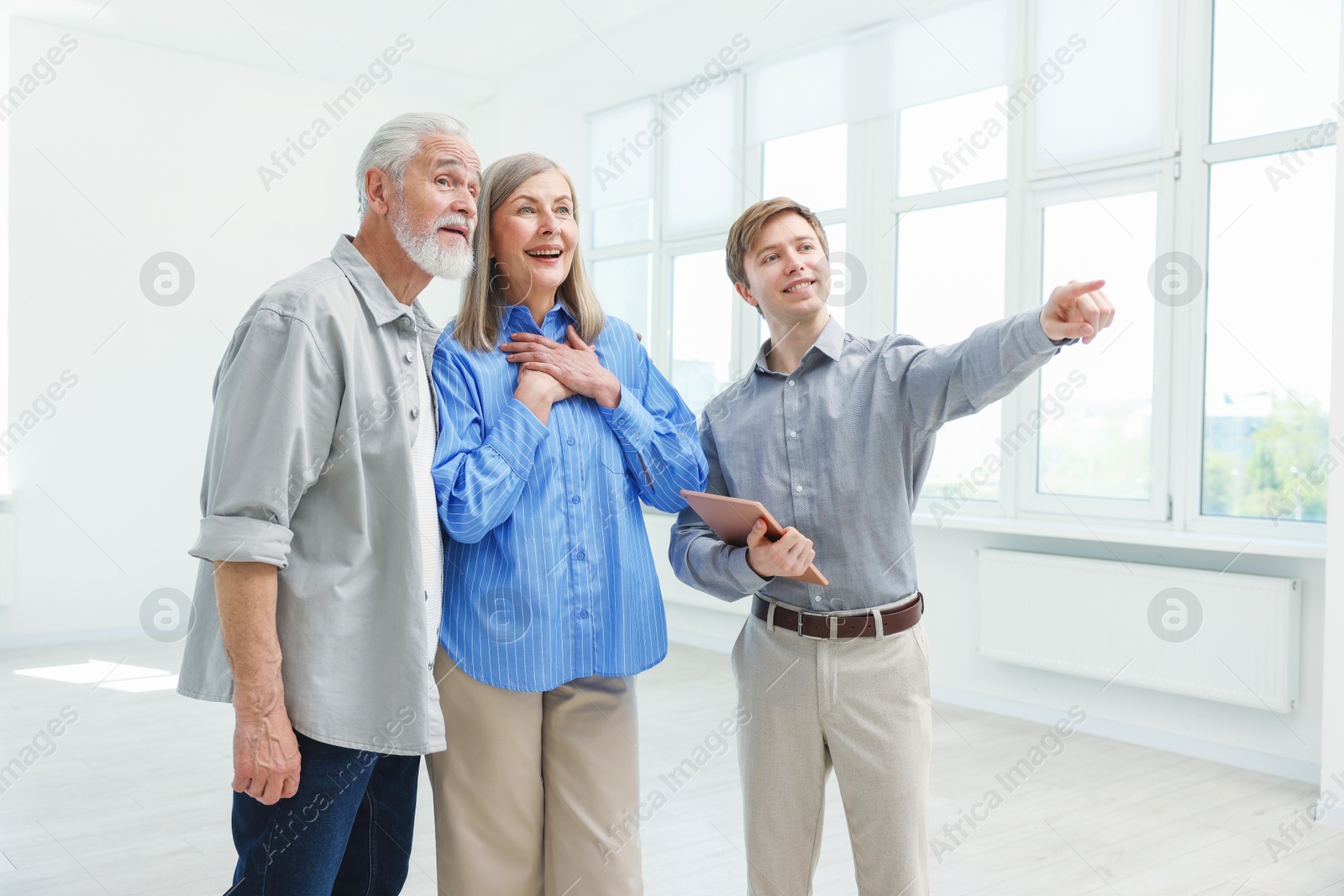 Smiling real estate agent showing apartment to couple indoors Photo of Smiling real estate agent showing apartment to couple indoors