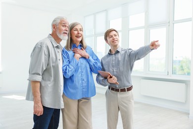 Photo of Smiling real estate agent showing apartment to couple indoors
