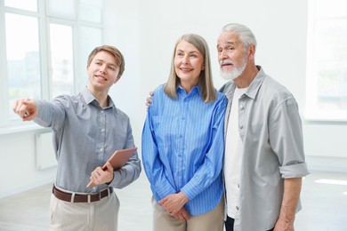 Photo of Smiling real estate agent showing apartment to couple indoors