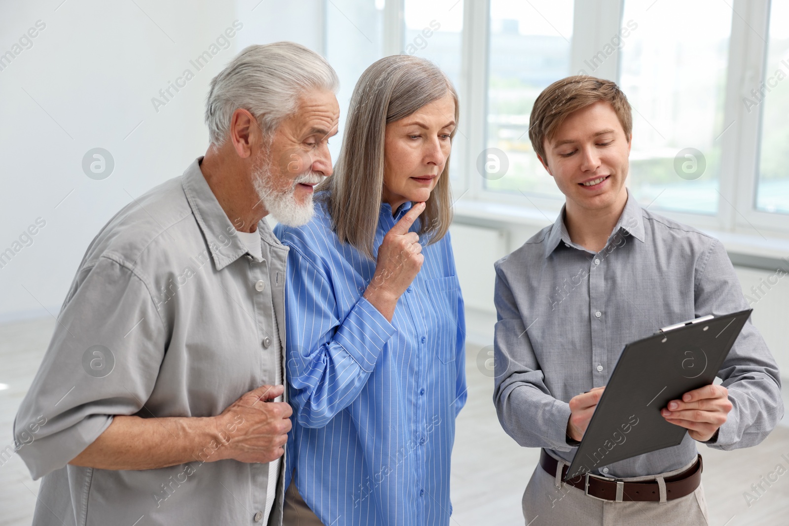Smiling real estate agent with clipboard working with couple at home Photo of Smiling real estate agent with clipboard working with couple at home