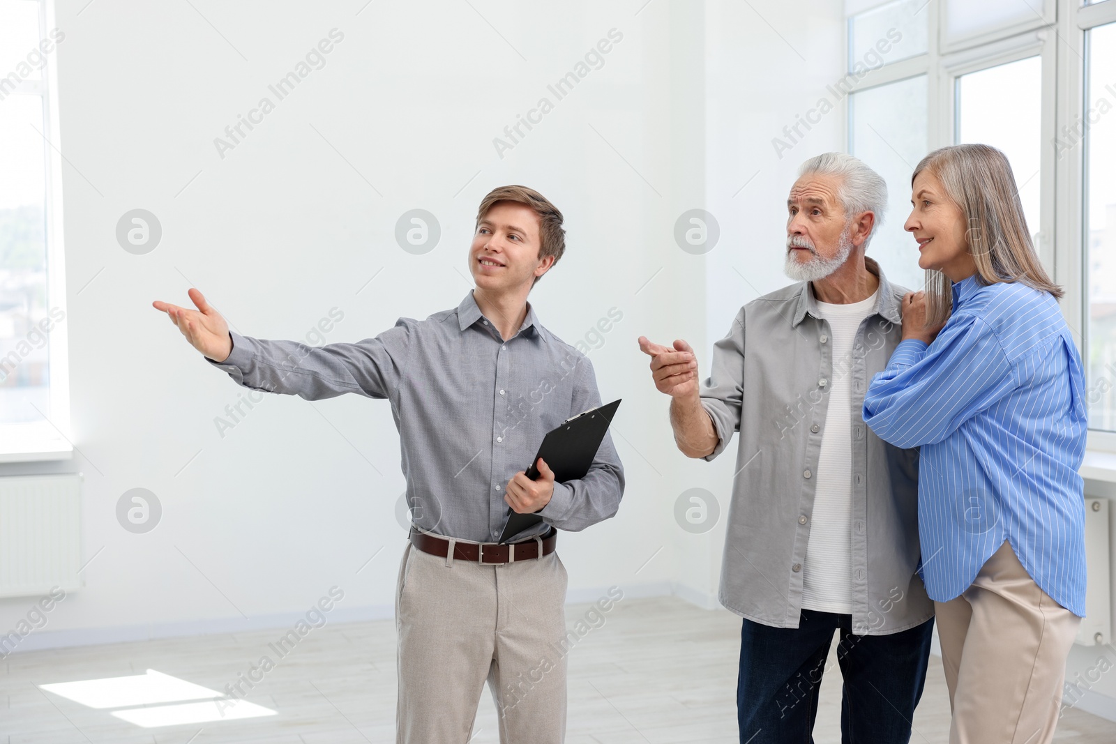 Smiling real estate agent showing apartment to couple indoors Photo of Smiling real estate agent showing apartment to couple indoors