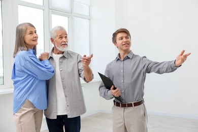 Photo of Smiling real estate agent showing apartment to couple indoors