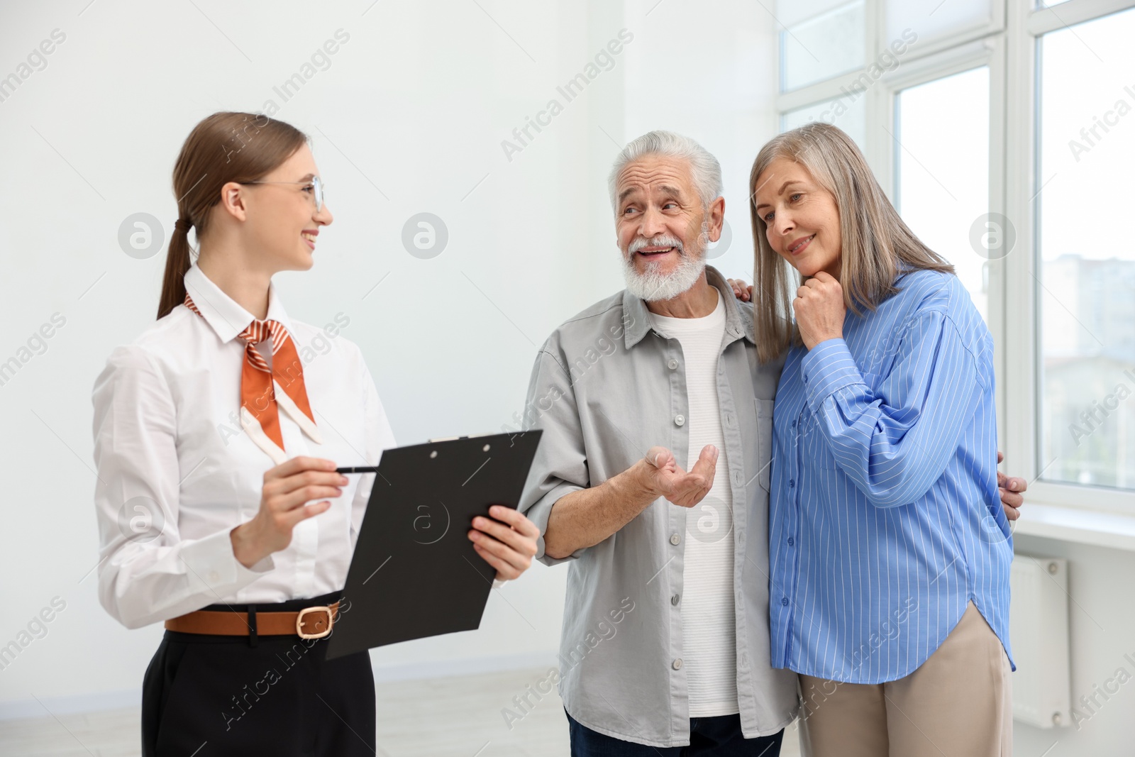 Smiling real estate agent with clipboard working with couple at home Photo of Smiling real estate agent with clipboard working with couple at home